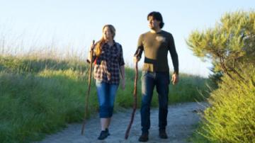 Woman and man standing on a hiking path holding walking sticks