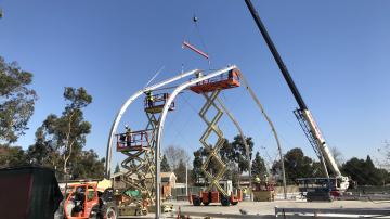 A crane lifts beams on a construction site