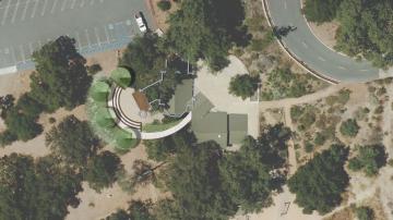 Aerial image of existing amphitheater adjacent to a parking lot. Showing a semi-circle and proposed small stage and tree plantings along the periphery