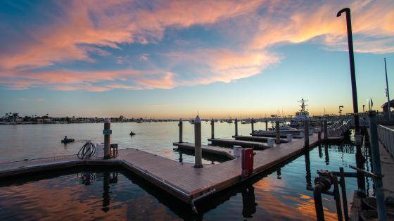 Docks in a glassy bay reflecting pink clouds at sunset