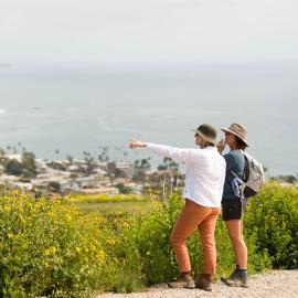 Two hikers on a trail overlooking the Pacific Ocean