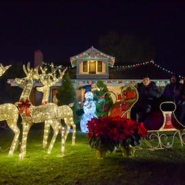 Family poses for photo in sleigh on Bennett Ranch House Lawn at Heritage Hill Historical Park. 