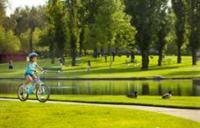 Young girl riding bicycle along a trail around a pond