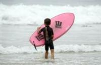 A child lifts a surfboard into the water at Salt Creek Beach.