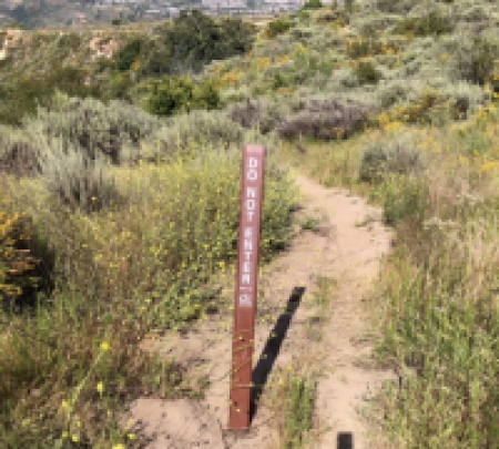 Grass lined dirt trail with a "Do Not Enter" sign