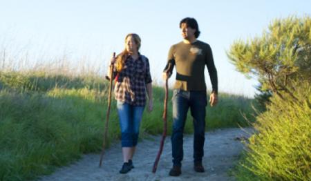 Woman and man standing on a hiking path holding walking sticks