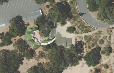 Aerial image of existing amphitheater adjacent to a parking lot. Showing a semi-circle and proposed small stage and tree plantings along the periphery